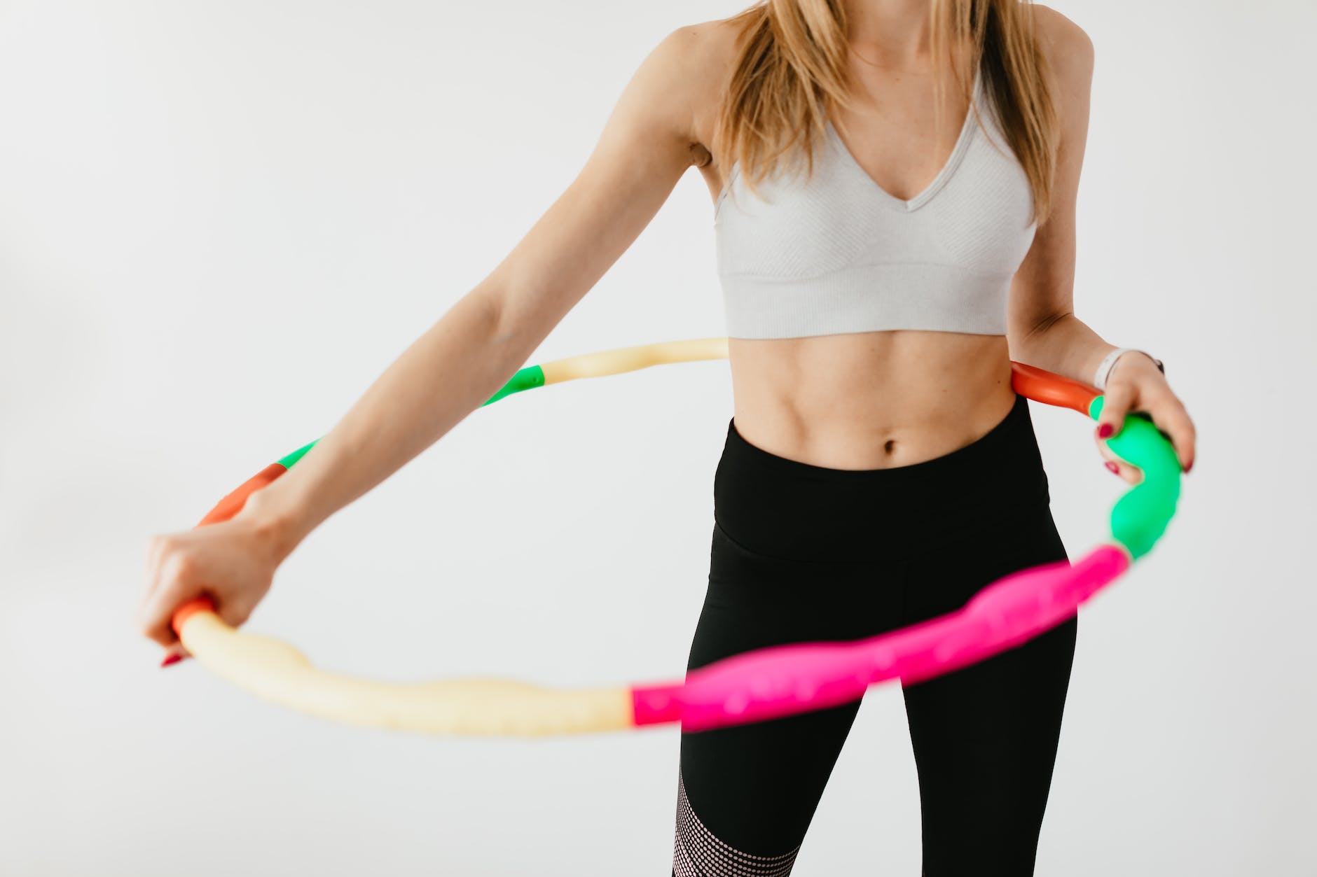 crop sportswoman exercising with gymnastic hula hoop
